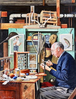 Elderly man in blue shirt tying fishing flies at a workbench surrounded by fishing nets and tackle