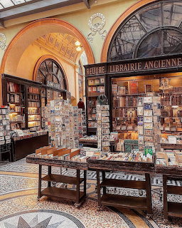 Historic bookstore interior with arched ceilings, shelves, tables, and many books and postcards