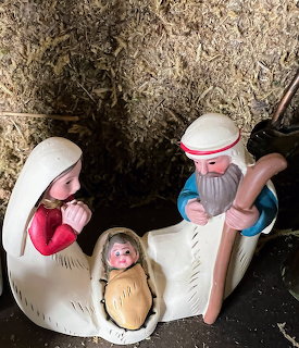 Nativity figurines showing Mary, Joseph, and baby Jesus in a small rustic stable