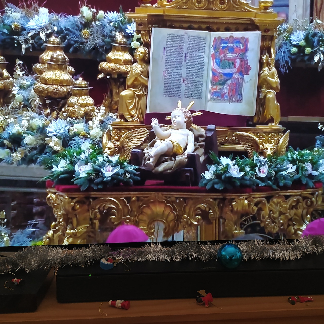 Golden altar with nativity scene, open religious book, Christmas trees, candles and ornaments