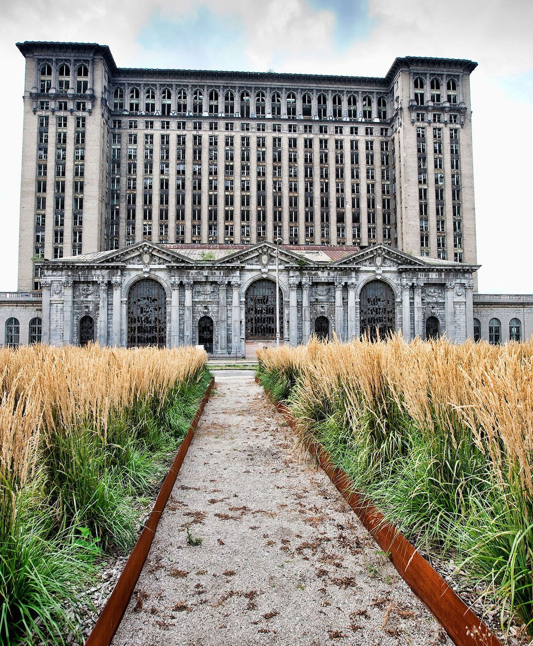 Michigan Central Station building with a path through tall grass leading to the entrance