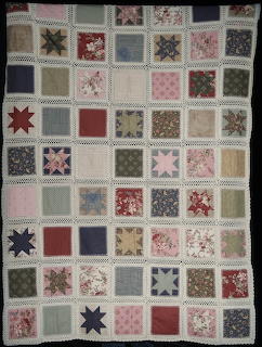 Patchwork quilt with squares in pink, red, blue, cream featuring stars and floral prints