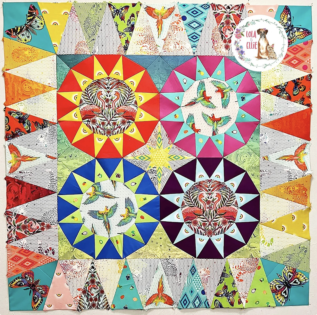 Bright patchwork quilt with star medallions, tigers, hummingbirds and triangular borders