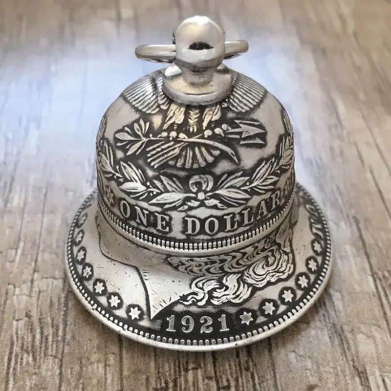 Handcrafted silver dollar coin bell with engraved details on a wooden surface