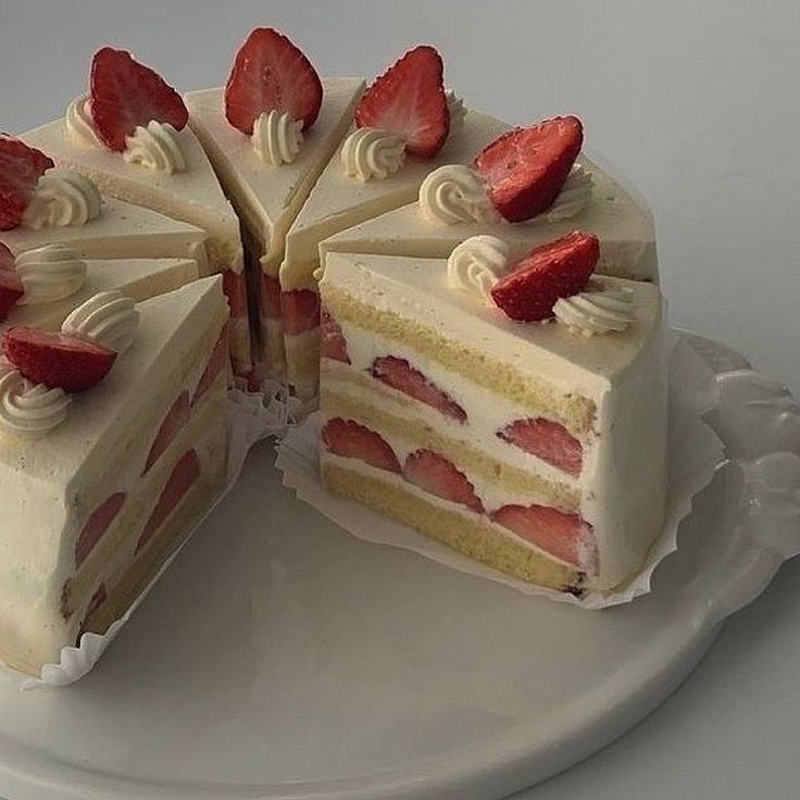 Sliced strawberry layer cake with cream frosting and fresh strawberries on top