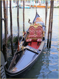 Venetian gondola tied beside wooden poles on a canal