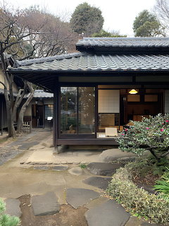 Traditional Japanese house with dark tiled roof, glass entrance, courtyard garden and stone pathway