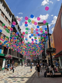 Vibrant balloons hanging over a pedestrian street in Andorra with shops and people