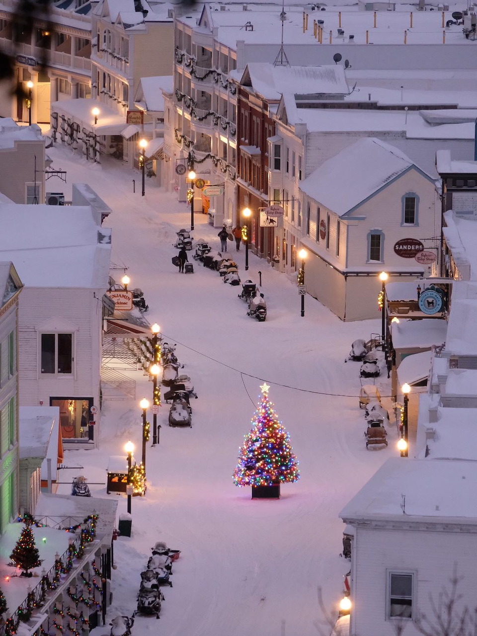 Main Street on Mackinac Island with shops, carriages, and visitors