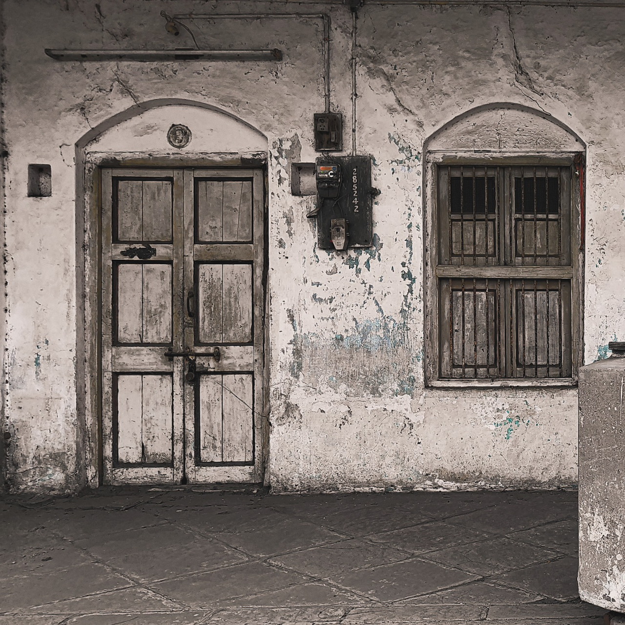 Old wooden door and barred window on a weathered stucco wall