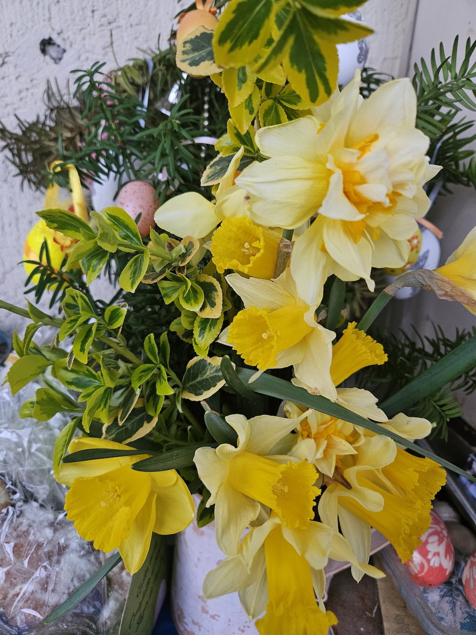 Close-up of a yellow daffodil bouquet with green leaves and stems outdoors