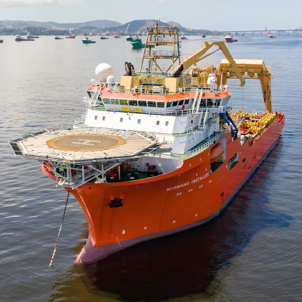 Orange offshore vessel NORMAND INSTALLER with crane and helipad in harbor