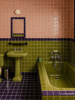 Retro bathroom with green and pink tiles, pedestal sink, and built-in bathtub with purple trim