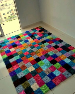 Colorful patchwork shag rug with many bright square patches on a light tiled floor