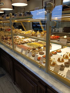 Glass bakery display counter filled with pastries, cakes, and breads at a French boulangerie