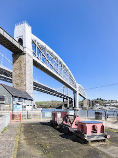 Royal Albert Bridge at Saltash with iron arch structure spanning the Tamar river and pink rail vehicle in foreground