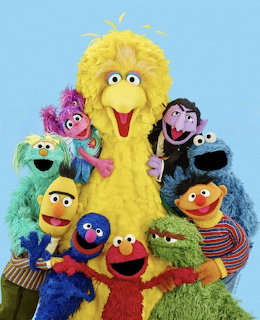 Group of Sesame Street muppet characters including Big Bird, Elmo, Cookie Monster, and friends posing together
