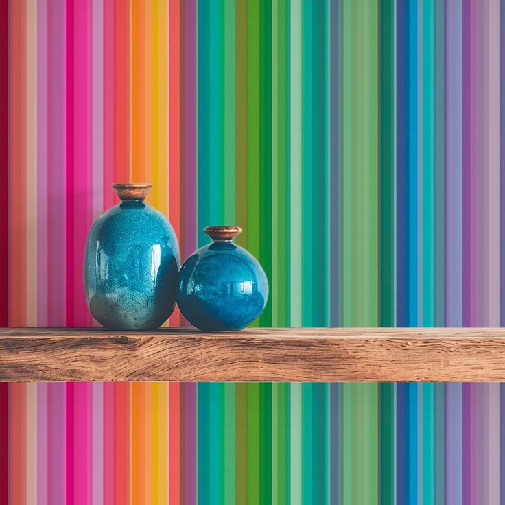 Two blue ceramic vases on a wooden shelf against a colorful vertical striped wall