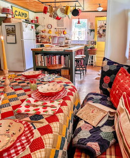Cozy country kitchen with patchwork quilt tablecloth, vintage decor, and colorful dishes on a set table