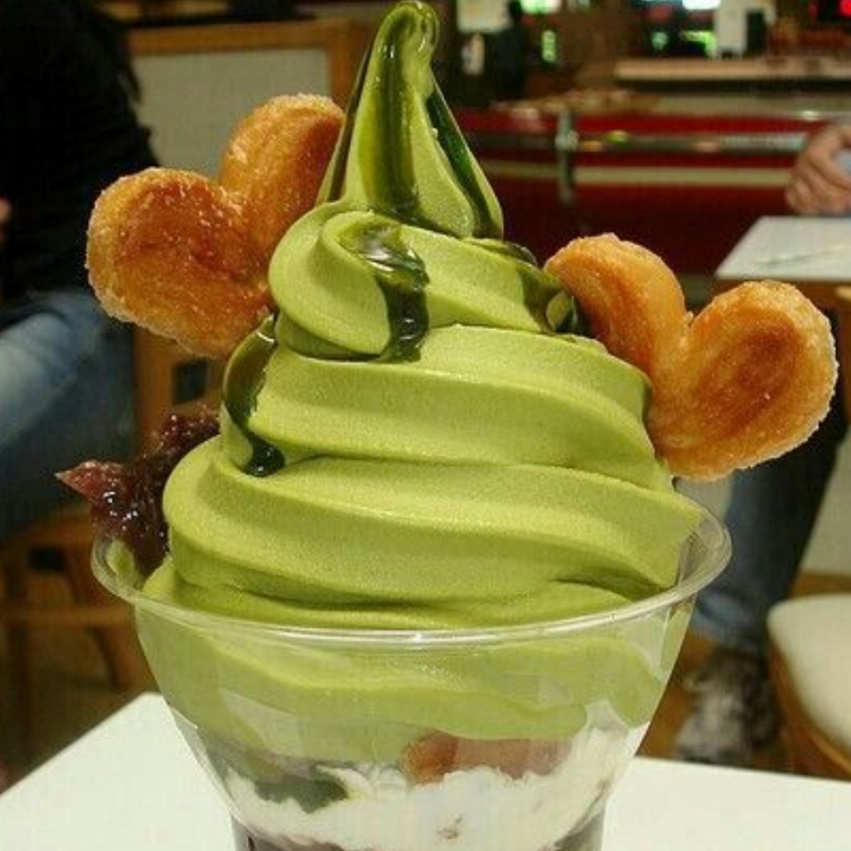 Matcha soft serve in a clear cup with pastry toppings, cream, and sweet beans