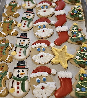 Rows of decorated Christmas cookies including Santa, snowman, tree, stocking, gingerbread man and star shapes