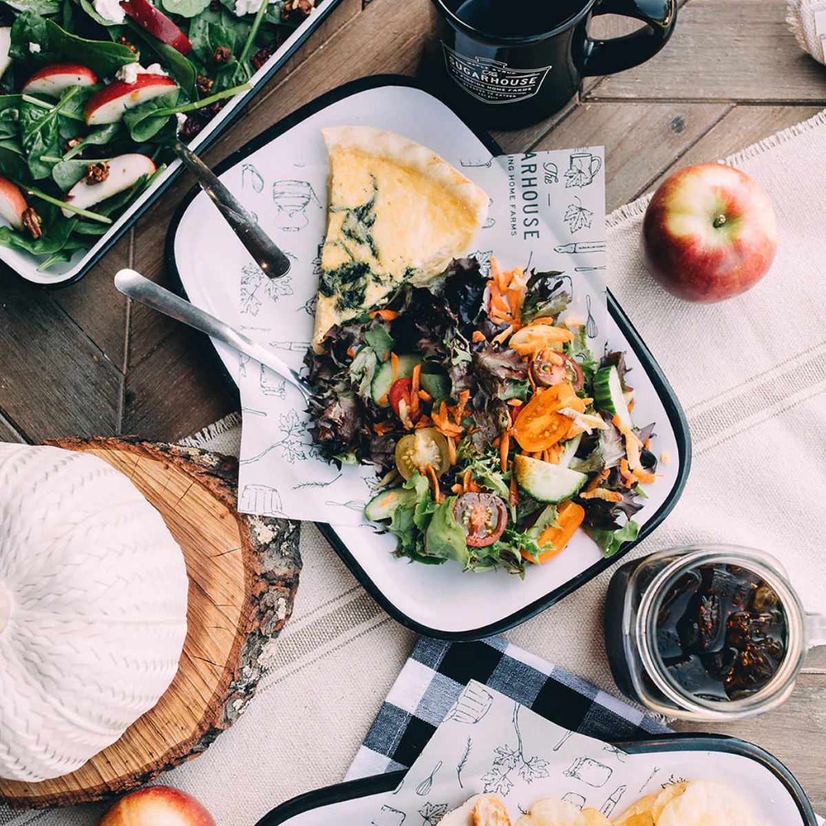 Overhead rustic table setting with salad, quiche, apple, coffee, and a glass drink