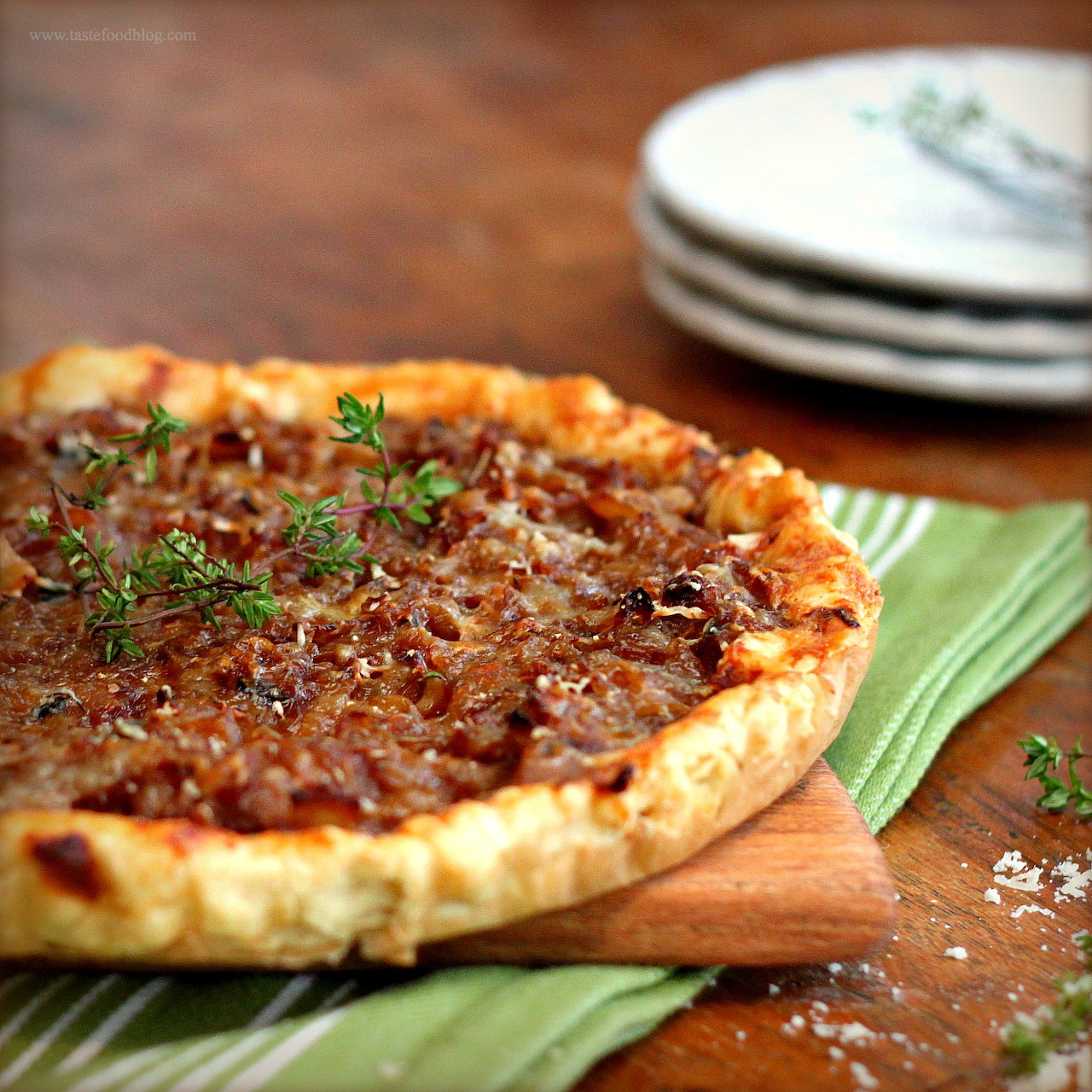 Caramelized onion tart with herbs on green napkin and wooden board