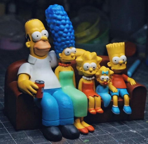 The Simpsons family figurines sitting on a colorful couch