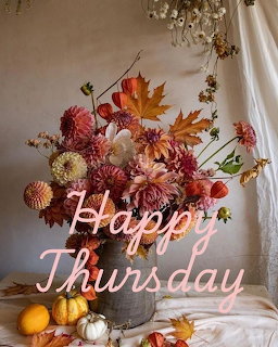 Autumn flower arrangement with dahlias and maple leaves in a metal bucket with small pumpkins