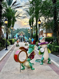 Whimsical frog statues playing drums and instruments on a resort pathway at twilight