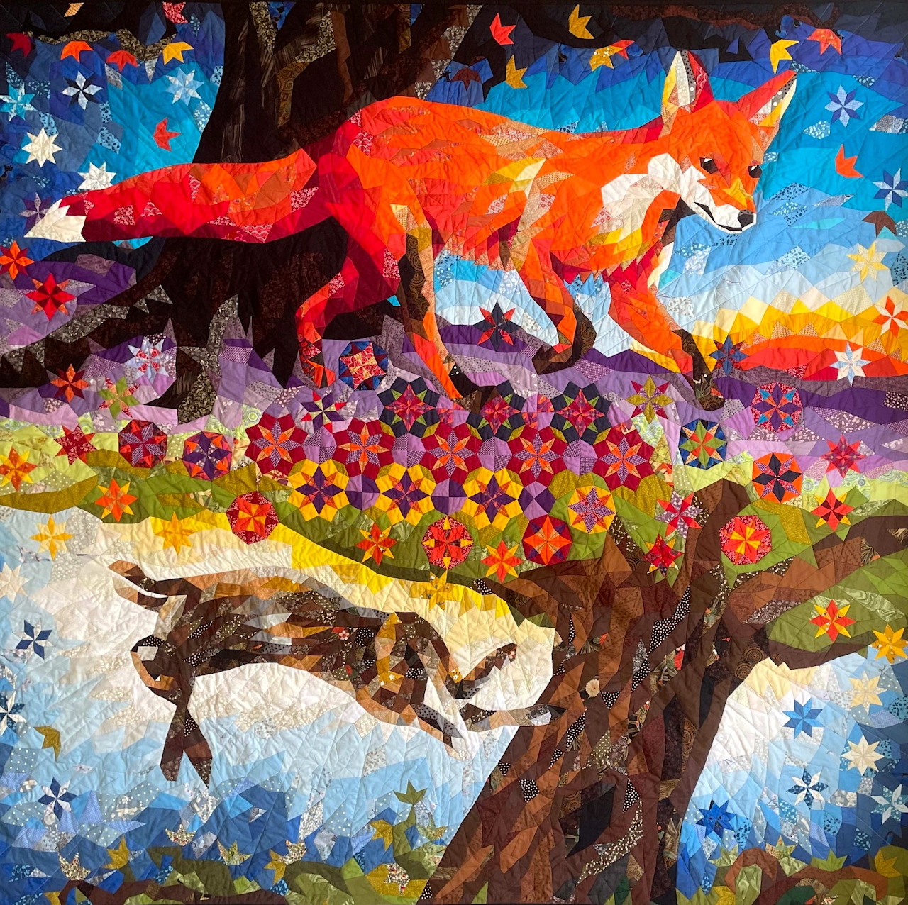 Quilted fabric art of a red fox and brown hare with flowers and stars in a mosaic patchwork style