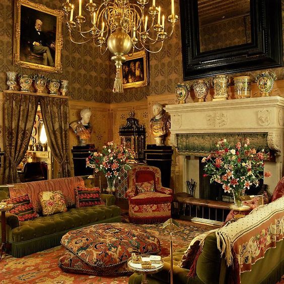 Ornate vintage sitting room with chandelier, fireplace, flowers, and patterned furniture