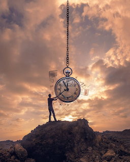 Silhouetted man touching a giant hanging pocket watch at sunset over rocky terrain