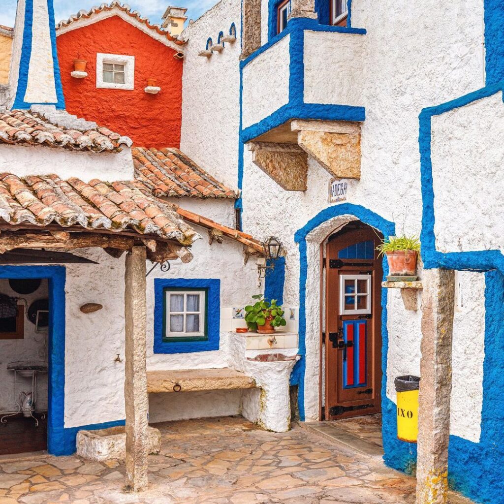White buildings with blue trim and terracotta roofs in a narrow Portuguese village street