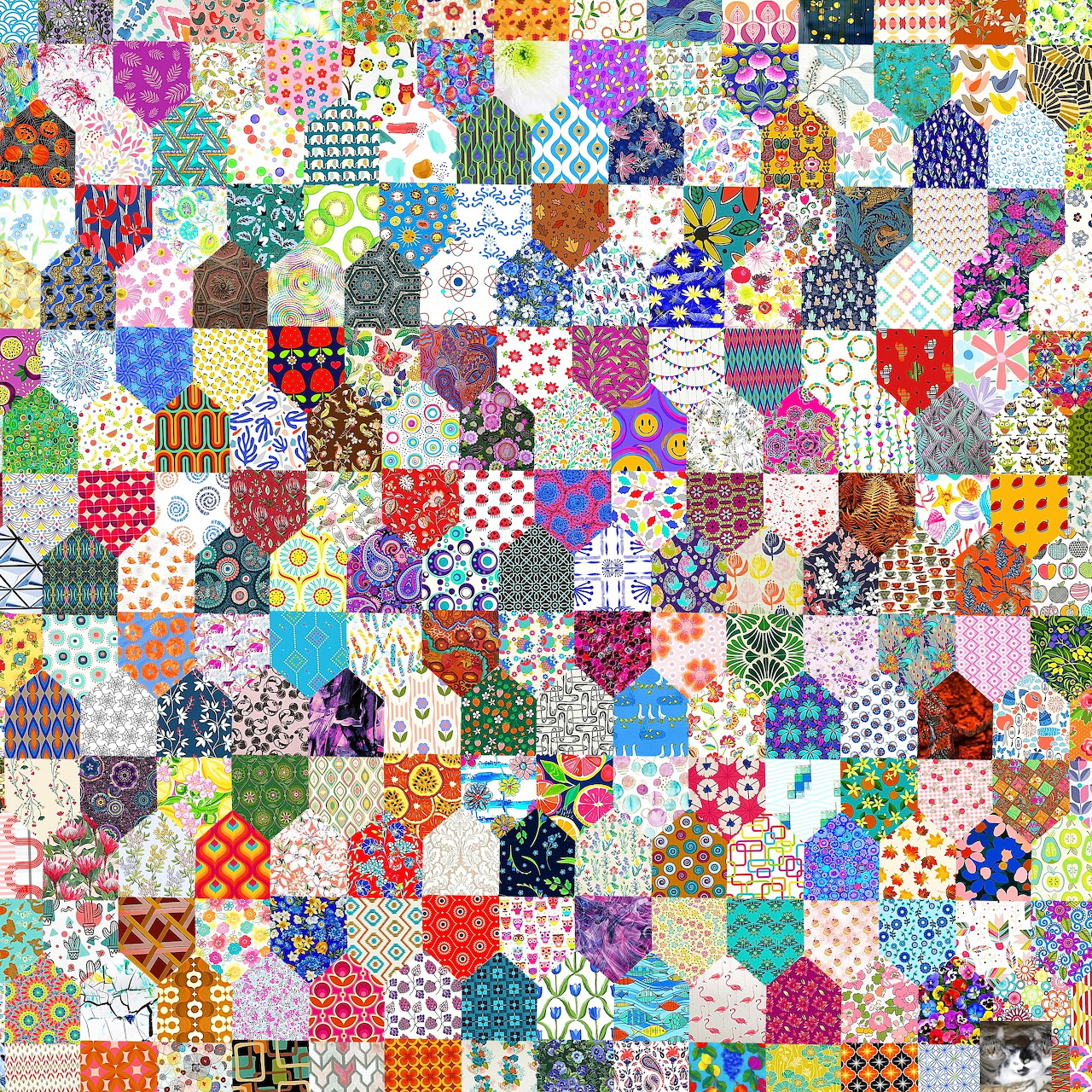 Colorful patchwork quilt made of small fabric squares with varied patterns including florals, polka dots, and geometric designs