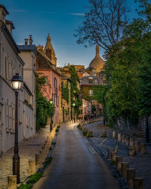 Cobblestone street in Montmartre at dusk with Sacré-Cœur basilica in the background, Paris