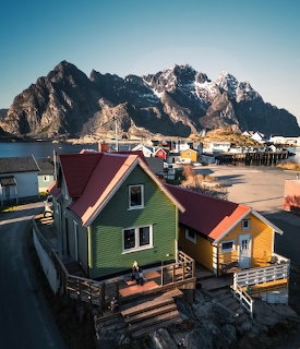 Colorful green and yellow houses in Lofoten Norway with mountains and fjord in background