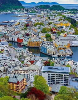 Aerial view of Alesund Norway with colorful buildings, waterways, and green mountains
