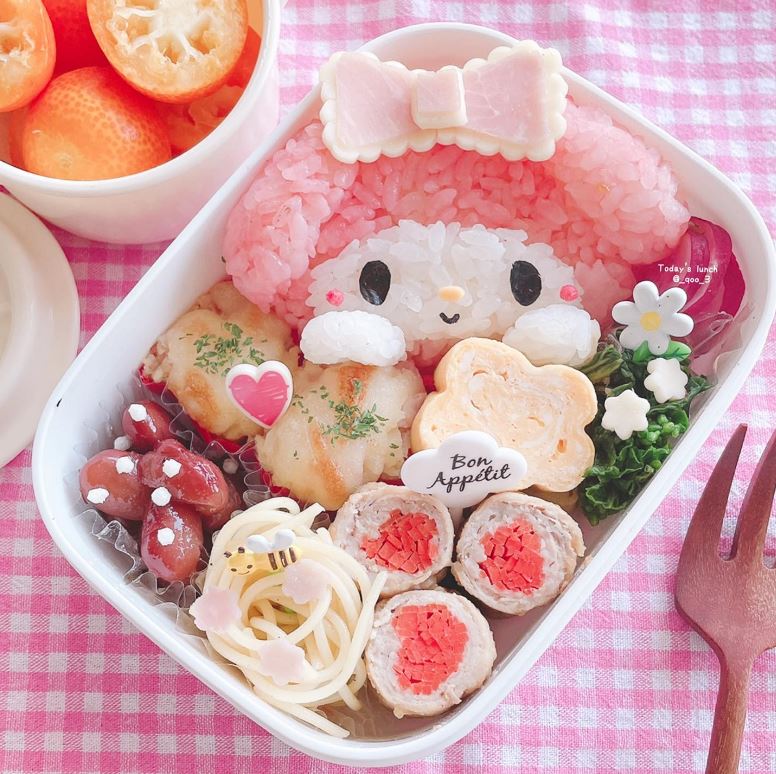 Kawaii bento box with character rice, decorated foods, and pink gingham tablecloth