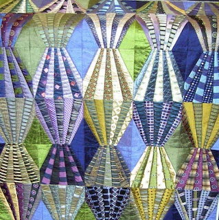 Colorful patchwork quilt with geometric diamond patterns in purple, green, blue and yellow fabrics