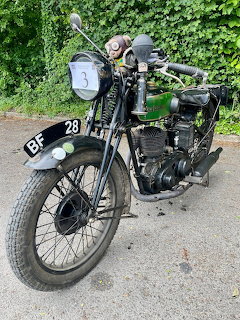 Black vintage New Imperial motorcycle with attached sidecar parked outdoors on paved road