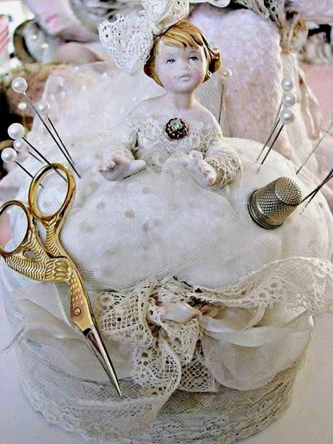 Vintage pin cushion doll in white lace dress with sewing needles, gold scissors, and thimble