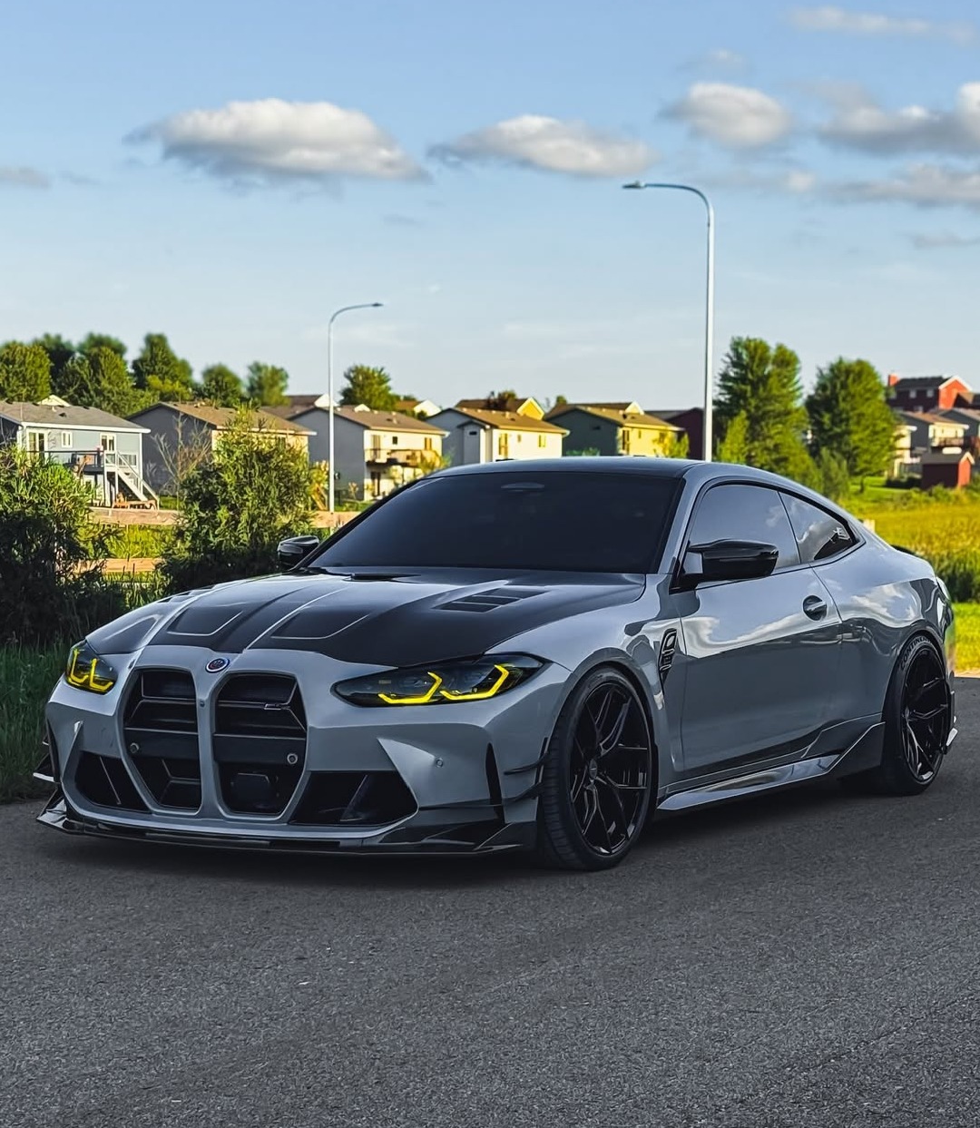 Gray BMW M4 Competition coupe parked on residential street