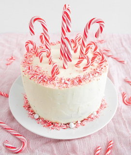 White cake topped with red and white peppermint candy canes and crushed candy sprinkles