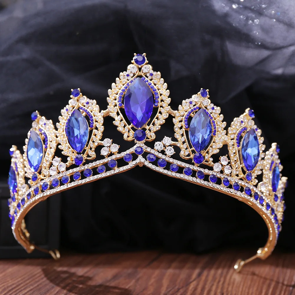 Gold tiara with blue sapphire stones and pearls on dark fabric