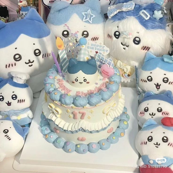 Two-tier birthday cake with Hachiware cat design surrounded by blue and white cat plush toys