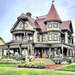 Large Victorian house with a turret, wraparound porch, and front lawn