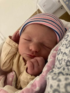 Sleeping newborn baby in a striped knit cap, resting on soft blankets
