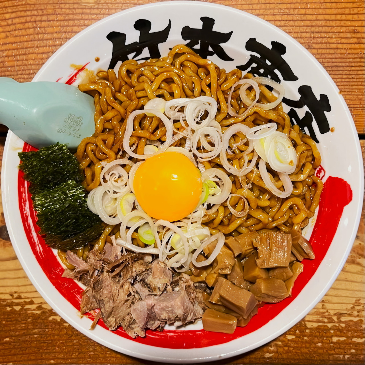 Bowl of abura soba ramen with egg yolk, scallions, seaweed, pork, and bamboo shoots