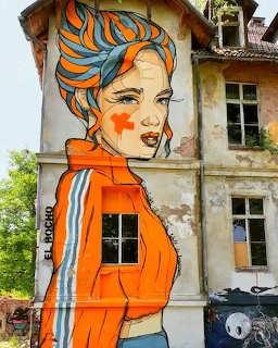 Colorful street art mural of woman with blue flowing hair on aged building wall